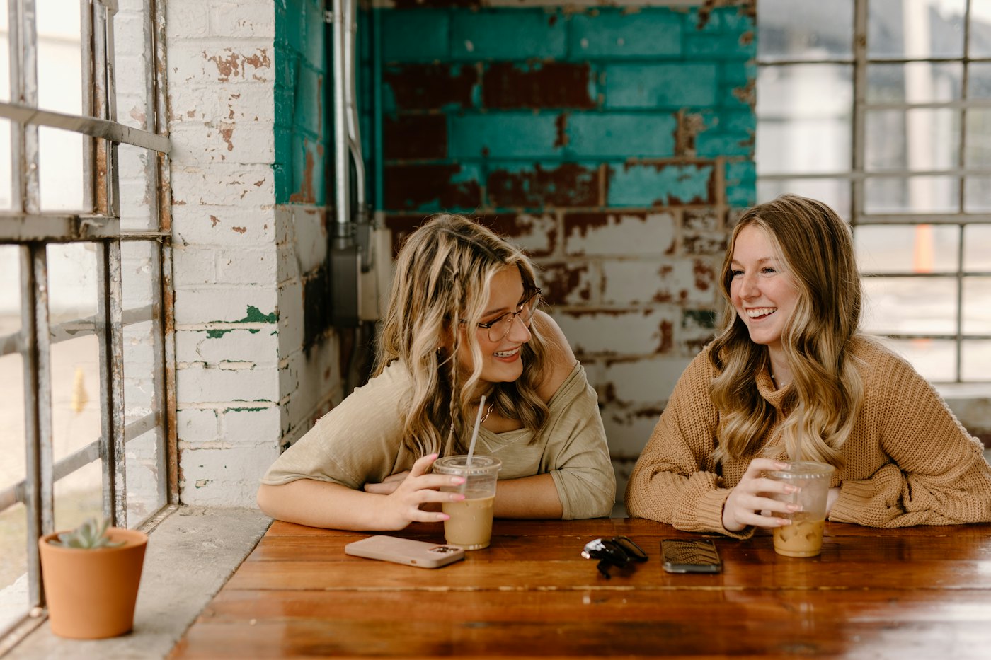 Two women laughing over drinks at a table