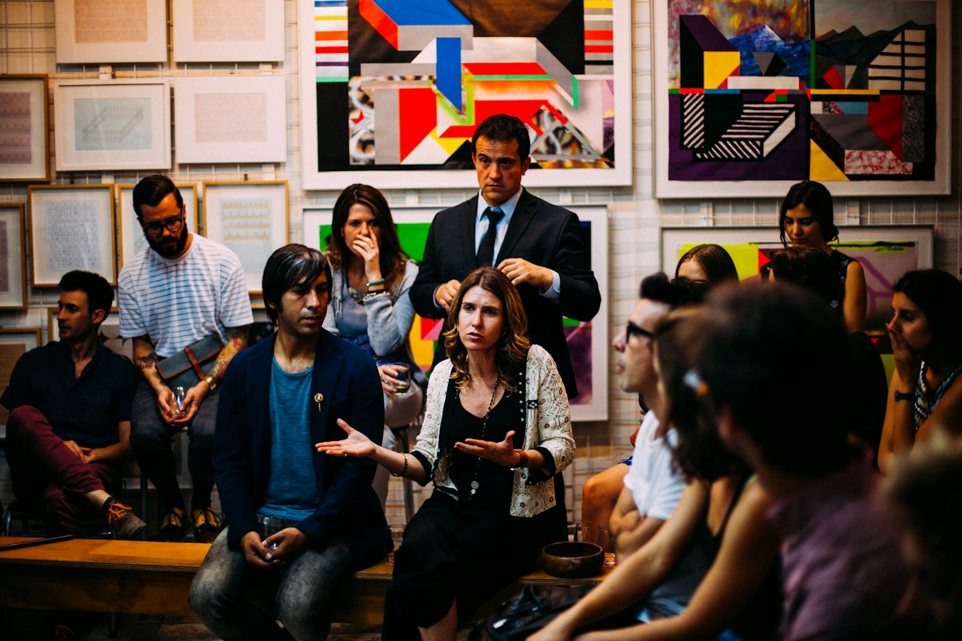 A crowd listening to a speaker in front of colourful paintings